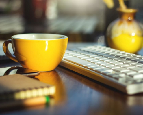 Gelbe Kaffeetasse neben Tastatur - Office Management Alexa - Virtuelle Assistenz