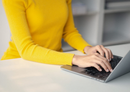 Frau in gelbem Pulli schreibt auf Laptop- Office Management Alexa - Virtuelle Assistenz - 04
